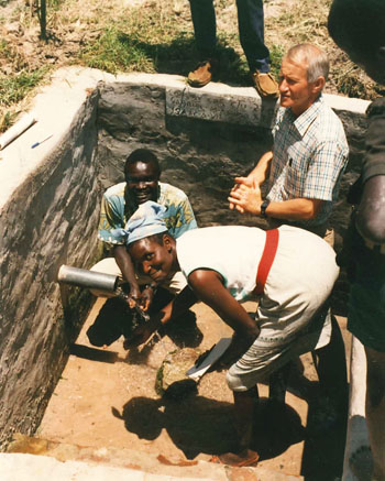 Photo top: John Orkar and family; photo above: John Hooyer with Isaac Agotre and Margaret Ejoga from CRS, checking a protected well (1989)