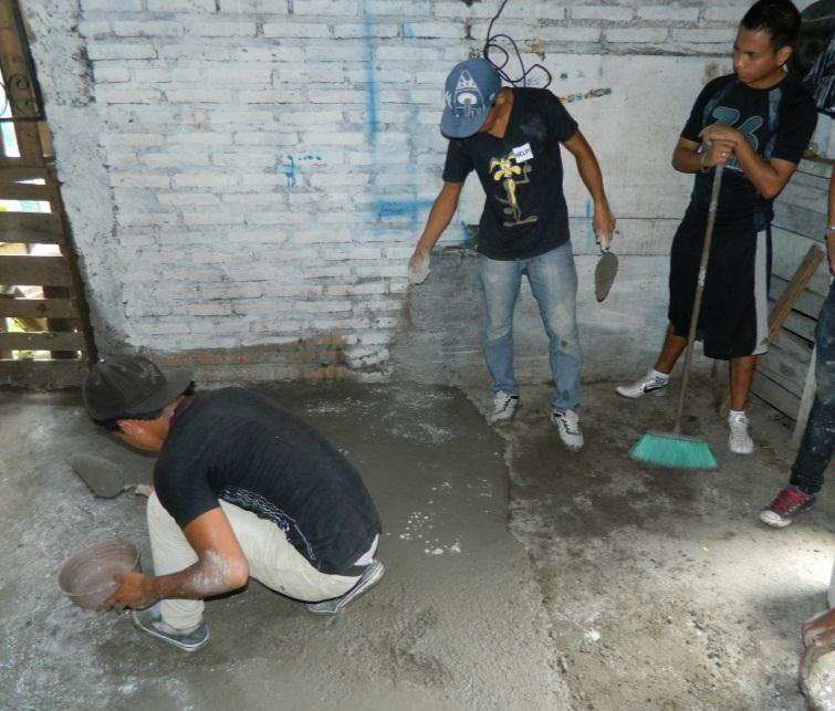 TOP: The community art exhibit work ABOVE: The youth working hard mixing cement for new floors