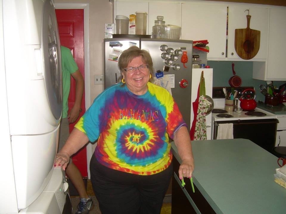Betty Bartlett with her newly painted cupboards and bright red door in the background