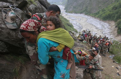 Soldiers assist a woman carrying a child on her back during rescue operations in Govindghat in the Himalayan state of Uttarakhand June 23, 2013.  REUTERS/Danish Siddiqui