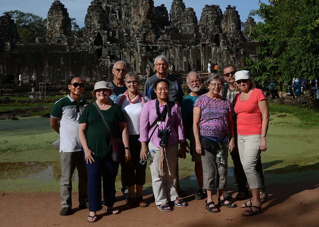 a group of people smiling in front of Cambodian ruins