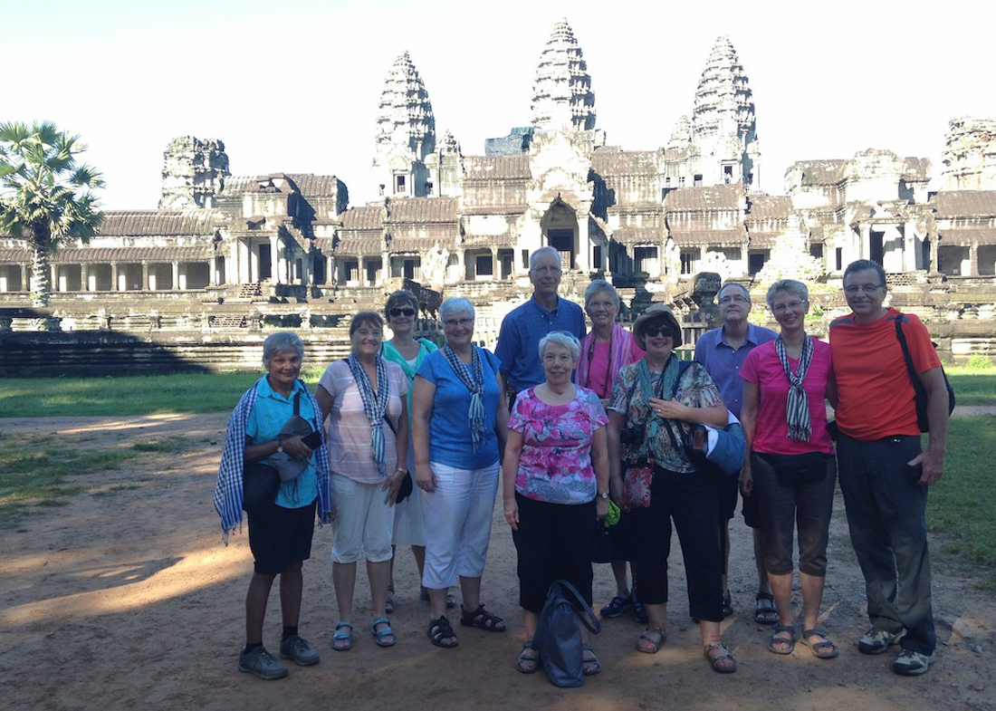 a group of people smiling in front of Cambodian ruins