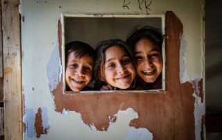 three kids smiling through an opening in lebanon