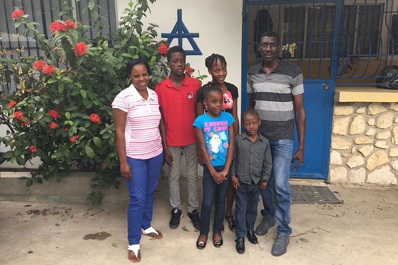 a Haitian family of six standing outside their home
