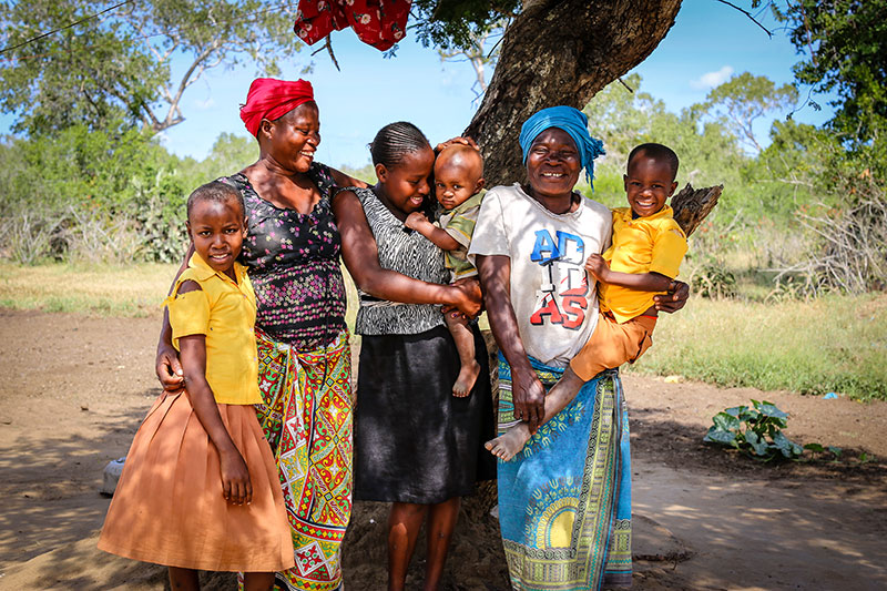 a Kenyan family smiling for the camera under the shade of a tree
