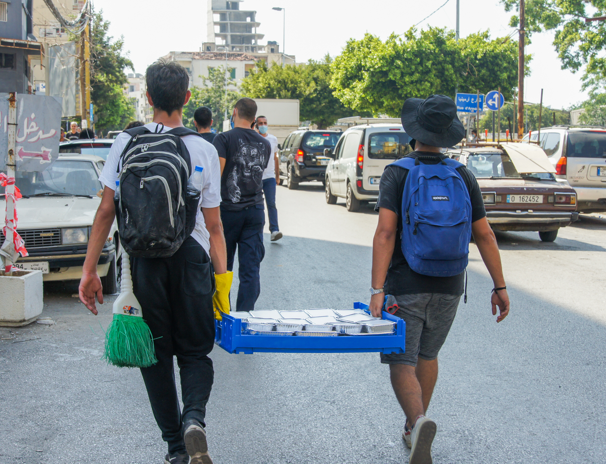 backs of men pictured carrying a pallet of meals to be given out in beirut