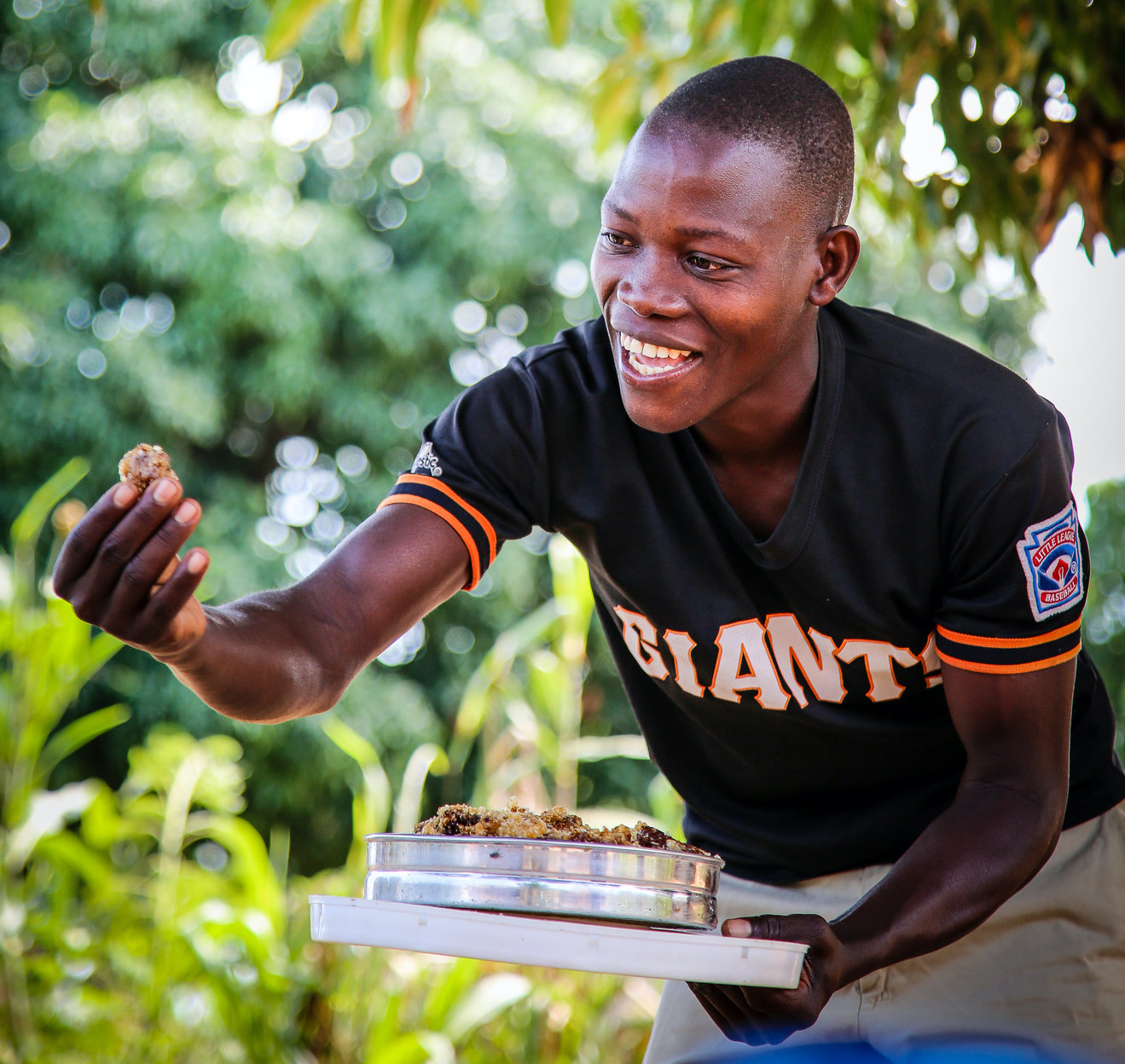 African man smiling and holding out food