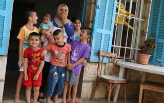 Syrian mother laughing in a doorway surrounded by her six children