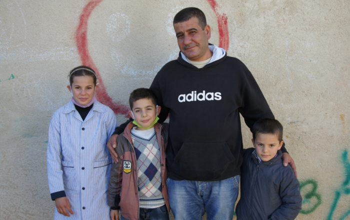 Syrian father standing with his daughter and two sons
