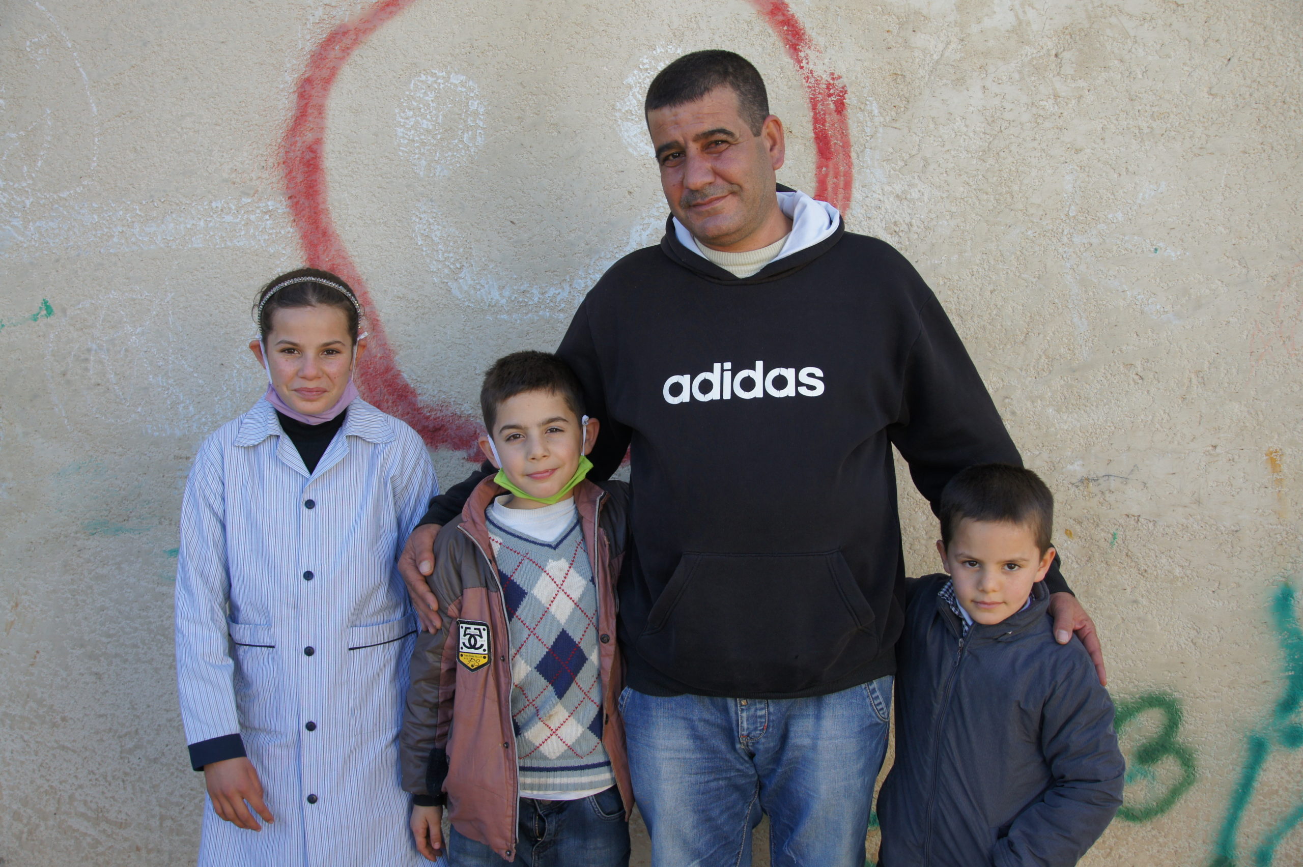 Syrian father standing with his daughter and two sons