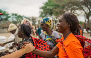 A gathering of Zambian mothers shaking hands and smiling