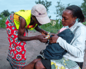 community health volunteer administering care to Kenyan mother and infant