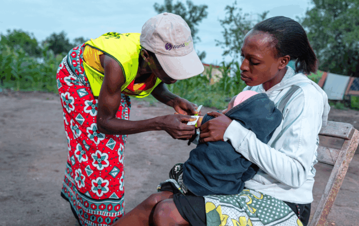 community health volunteer administering care to Kenyan mother and infant