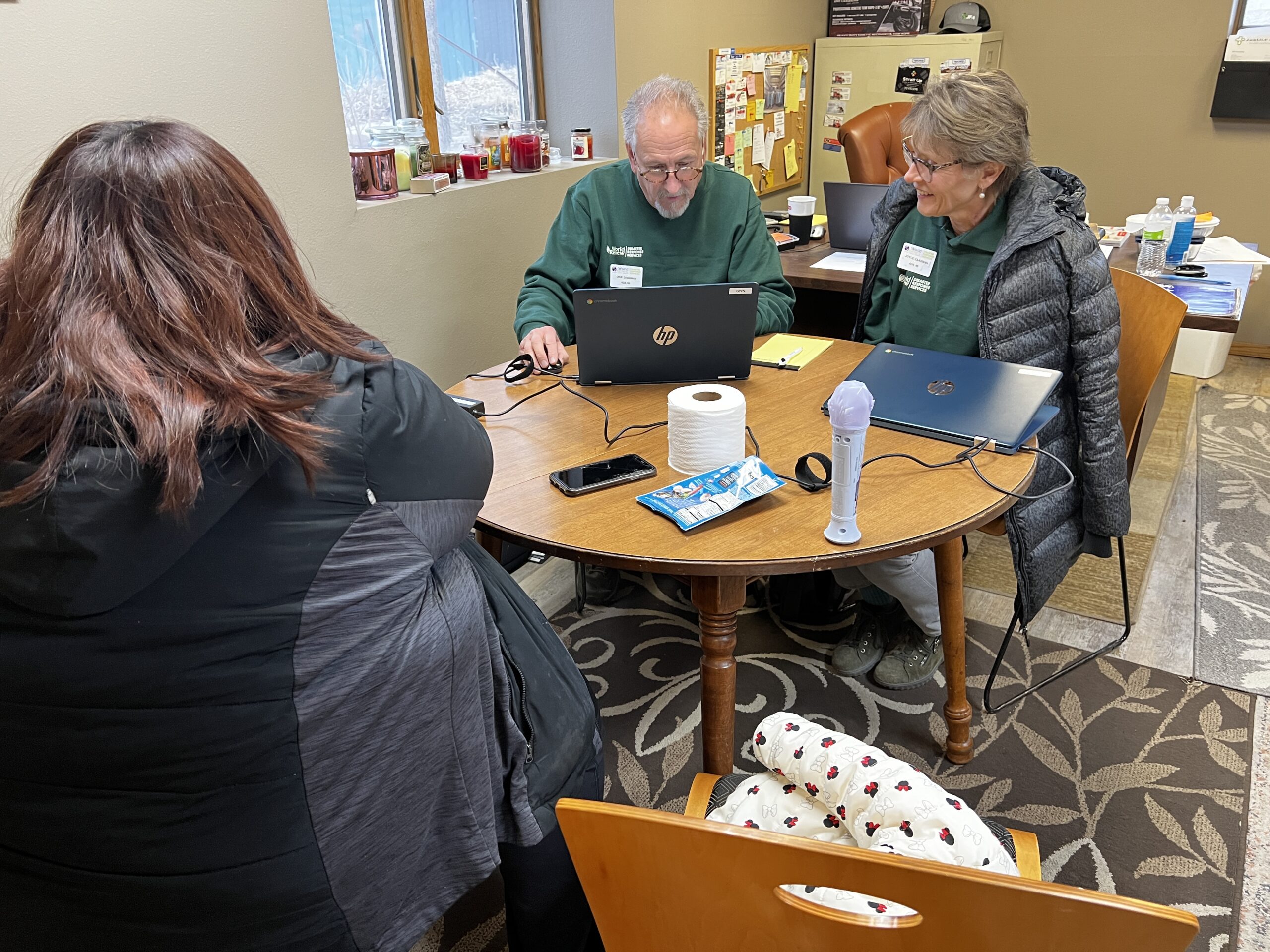World Renew Disaster Response Services Needs Assessment volunteers sit at table with applicant impacted by Iowa floods.