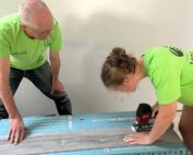 two volunteers trimming flooring planks