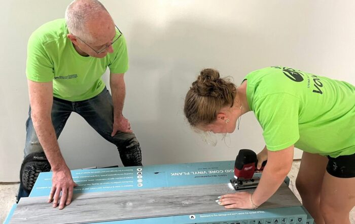 two volunteers trimming flooring planks