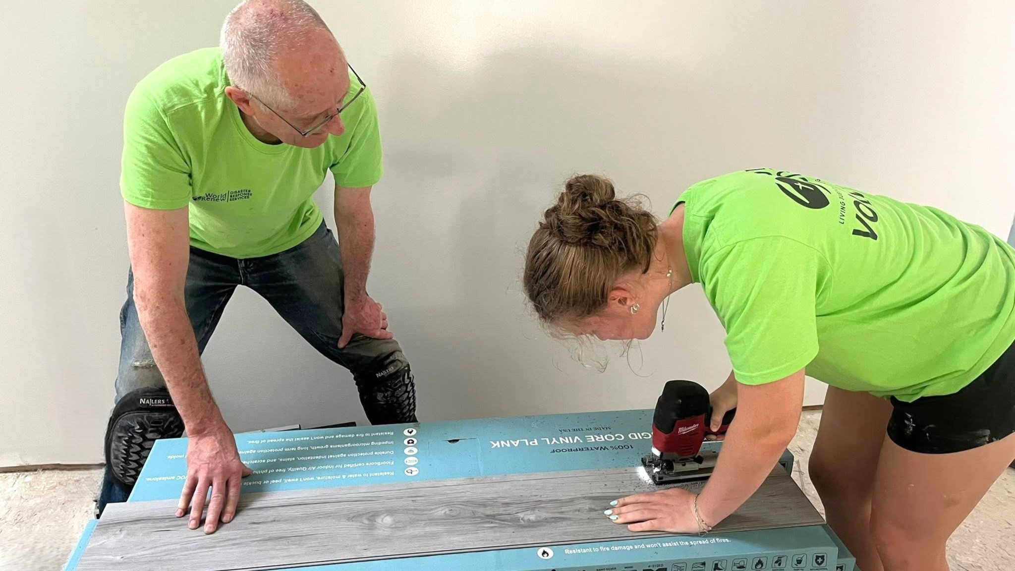 two volunteers trimming flooring planks