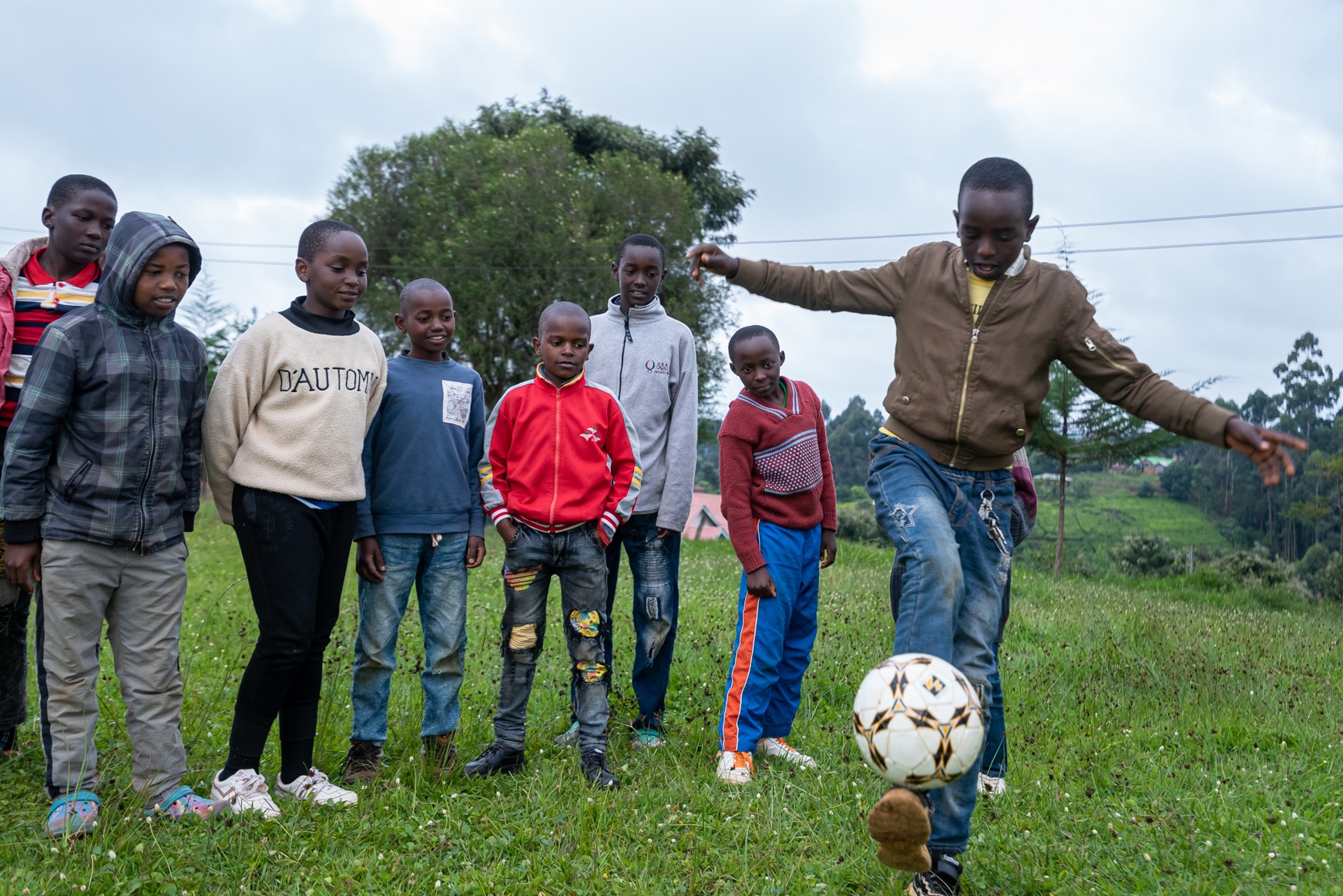 Boy juggling soccer ball with school children watching