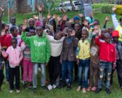 Group of school children smiling and waving at camera