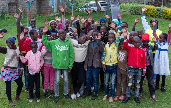 Group of school children smiling and waving at camera
