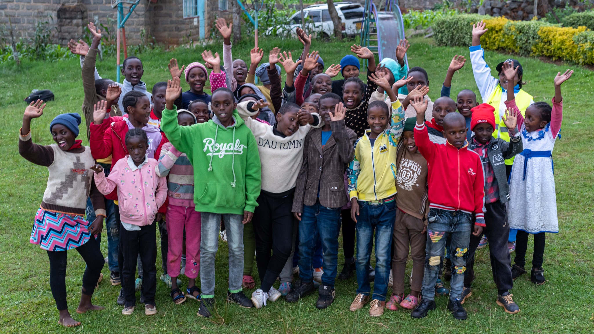 Group of school children smiling and waving at camera
