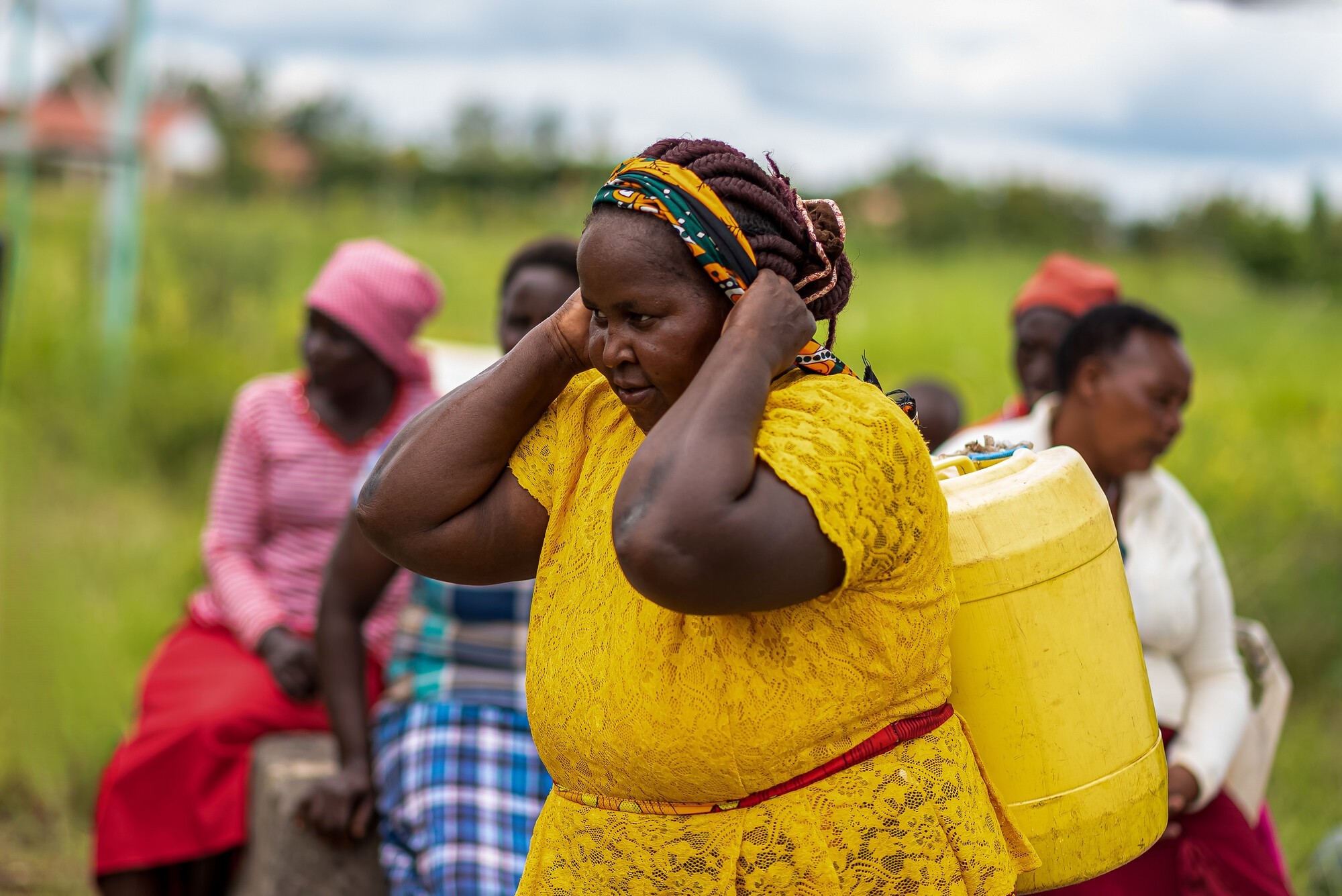 woman wearing yellow and carrying a yellow water jug on her back