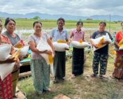 group of people lined up holding grain bags