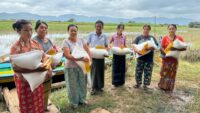 group of people lined up holding grain bags