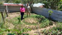 Two adults standing next to a circular kitchen garden designed to conserve water and improve food production.