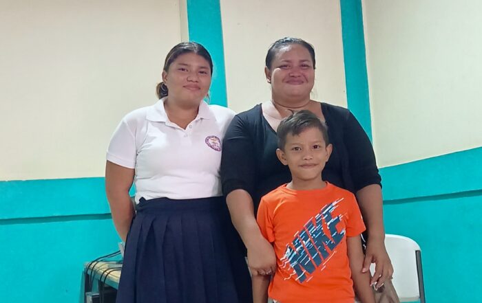 Three people stand indoors at a community center, facing the camera.